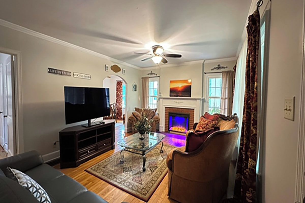 A living room with a television, a fireplace, and a ceiling fan.