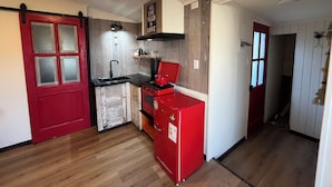 Une cuisine de taille réduite avec un réfrigérateur rouge, une cuisinière et un évier.