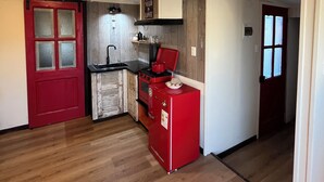 Une cuisine de taille réduite avec un réfrigérateur rouge, une cuisinière et un évier.