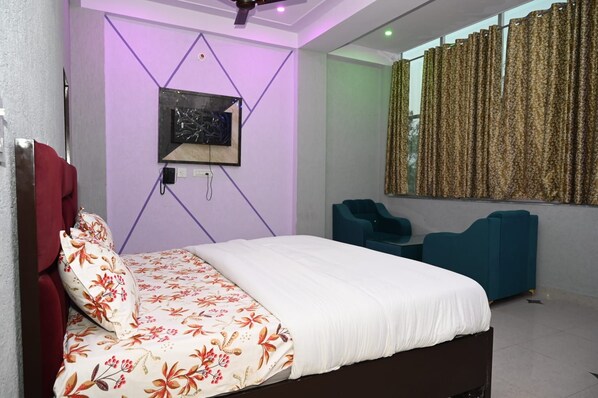 A modern bedroom with a bed, a TV mounted on the wall, and a window with curtains.