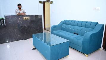 Un área de recepción con un mostrador de mármol, un sofá azul y una mesa de centro de vidrio.