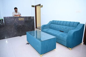A reception area with a marble reception desk, a blue sofa, and a glass coffee table.