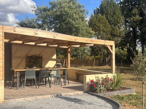 Un patio al aire libre con una pérgola de madera, una mesa y sillas.