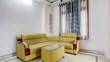 A living room with a yellow sofa set, a glass coffee table, and a ceiling fan.