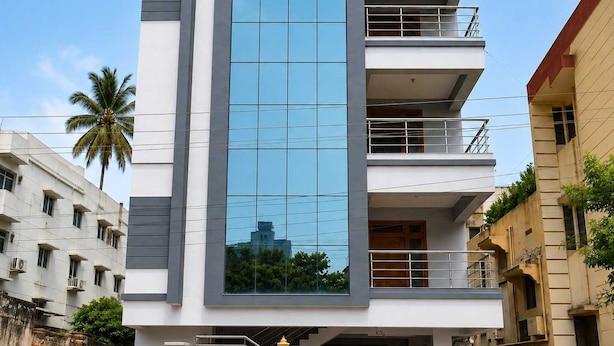 Um edifício moderno de vários andares com fachada de vidro central, varandas em cada pavimento e telhado plano.