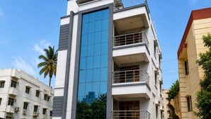 Um edifício com várias andares, fachada de vidro marcante, varandas e entrada protegida por grades.