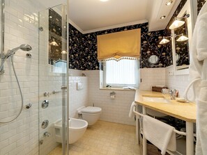 A bathroom with a glass-enclosed shower, a toilet, bidets, a sink with a mirror, and a window with a curtain. - Holiday Apartment 3 \"hanne Nute\" (Kuehlungsborn)