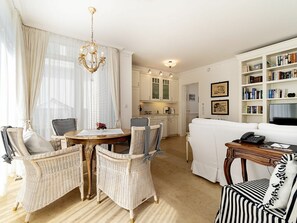 Ein Wohnzimmer mit Rattanmöbeln, einem Esstisch und einer Küche im Hintergrund.