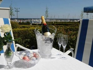 A table with a bottle of champagne in an ice bucket, two glasses, a vase with a white rose, and a bowl of assorted candies. - Holiday Apartment 3 \"hanne Nute\" (Kuehlungsborn)