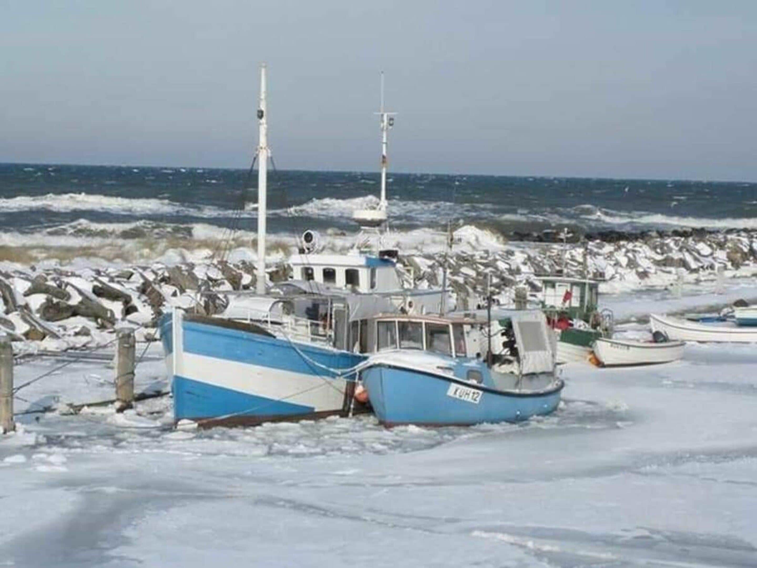 Jäässä loukkuun jäänyt vene kallioisen rannan lähellä.