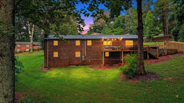 A two-story brick house with a deck and a covered outdoor area.