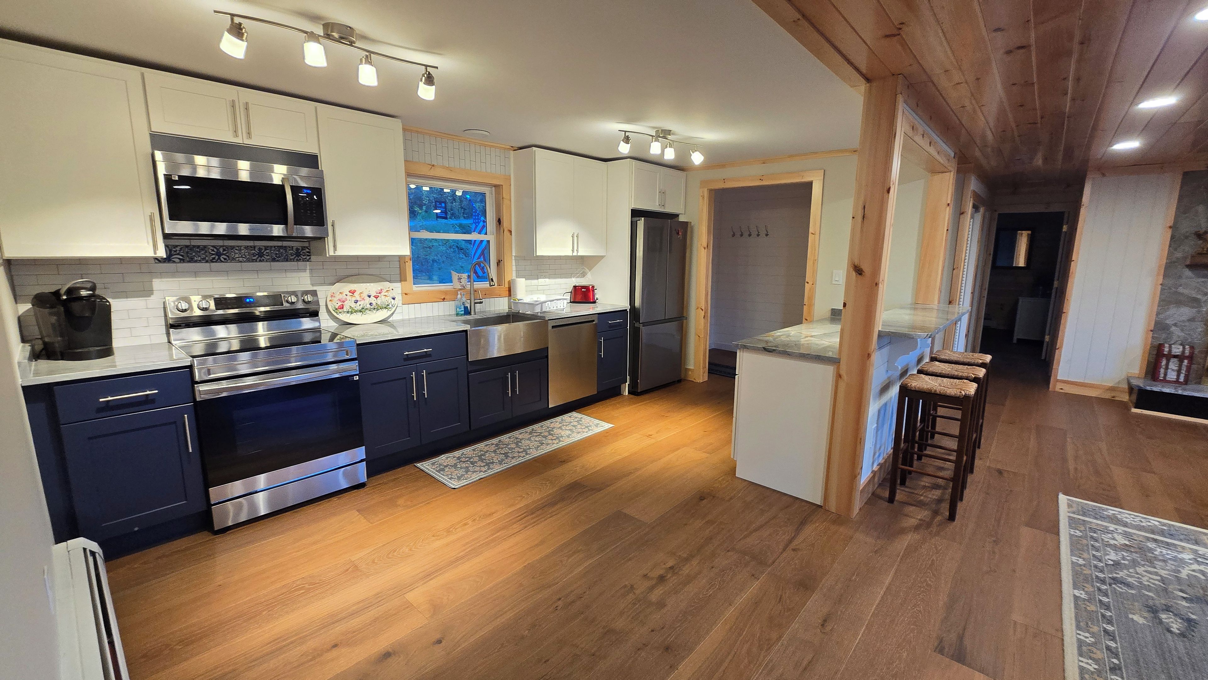Eine moderne Küche mit Edelstahlgeräten, Holzböden und einer Bar.