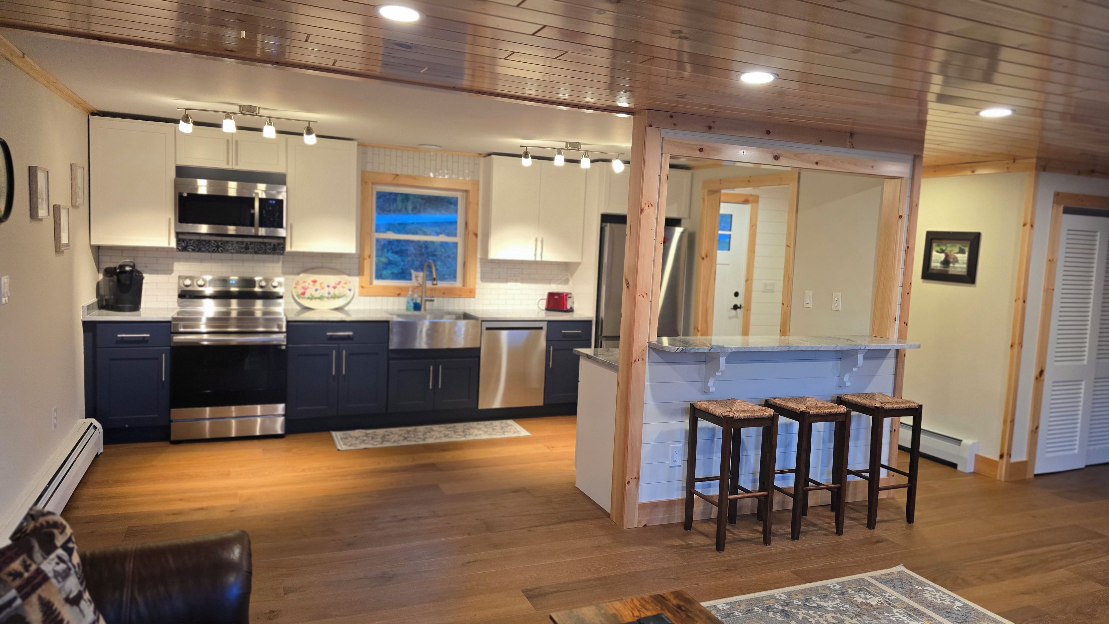 Eine moderne Küche mit Edelstahlgeräten, einer Bar mit Hockern und Holzböden.