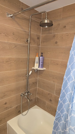 Un espacio de ducha con cabezal de ducha de mano y bañera blanca.