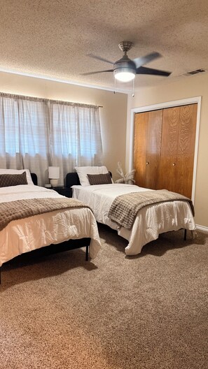 A bedroom with two beds, a ceiling fan, a wooden wardrobe, and a carpeted floor. - Cozy Townhome w/ Fireplace, 3 Baths, Near DFW Airport (Lewisville)