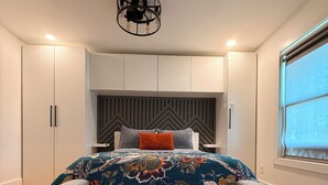 Un dormitorio con una cama grande, un cabecero moderno y armarios empotrados.