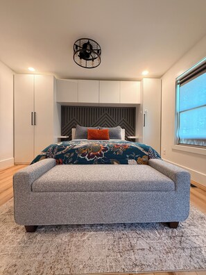 Een slaapkamer met een groot bed, een modern hoofdeinde en inbouw kasten.