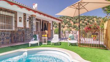A house with a swimming pool, outdoor seating, and a view of a vineyard.