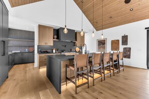 A modern kitchen with a central island, wooden cabinets, and pendant lighting. - Wasatch View - Luxury Alpine Retreat with Private Hot Tub and Mountain Views (Daniel)