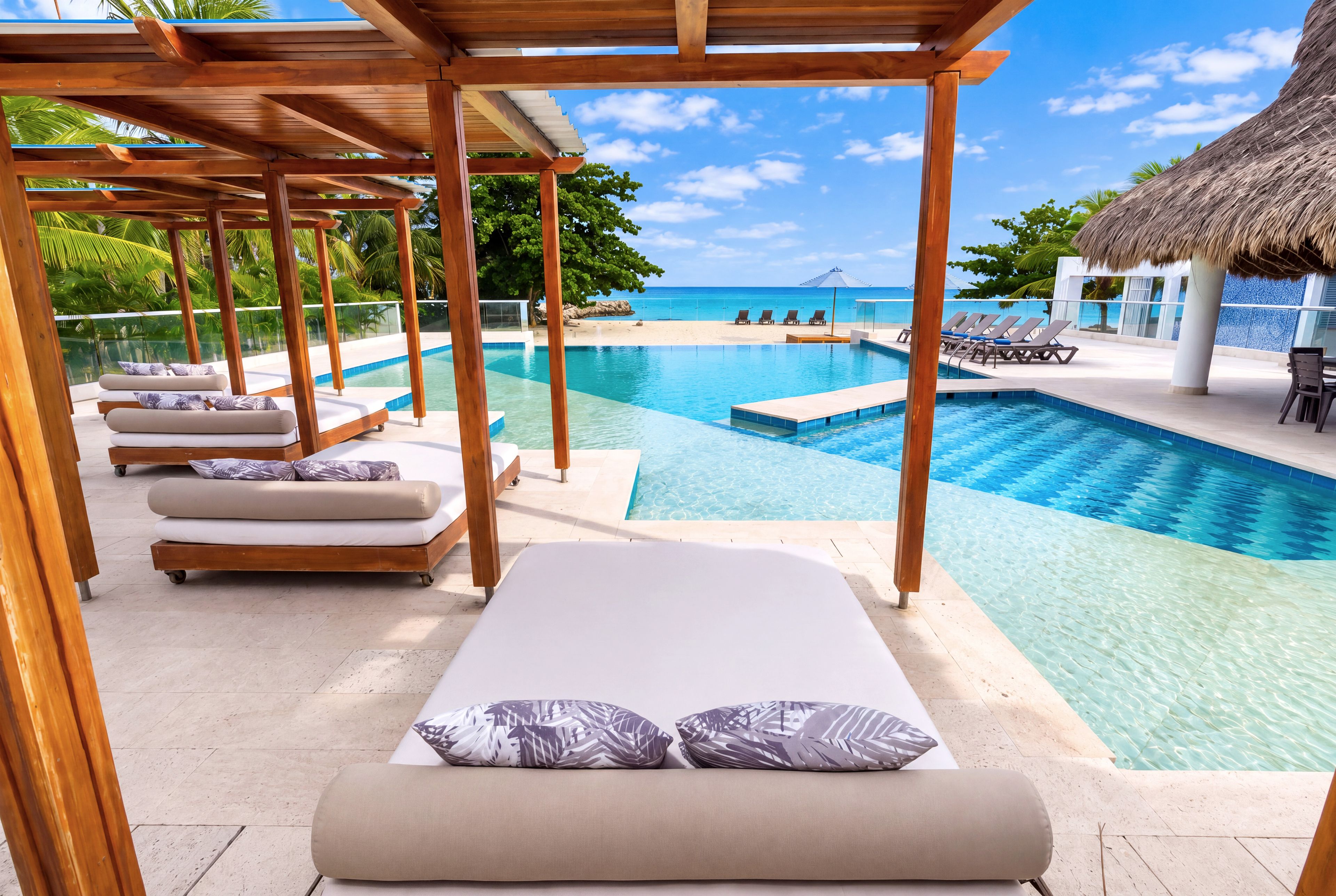 A poolside area with lounge chairs and a view of the ocean.