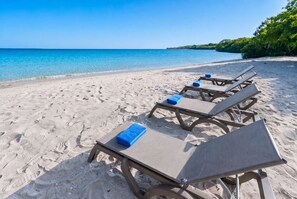 A beach with sun loungers and towels, clear blue water, and a sandy shore. - Modern Luxury Villa with Resort Pool  Bright Open Spaces Near Cartagena Beaches (Bolívar)