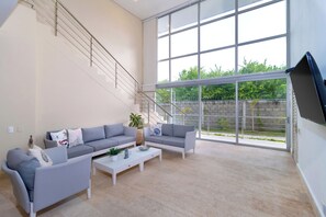 A spacious living room with a grey sofa set, a coffee table, and a staircase leading to an outdoor area. - Modern Luxury Villa with Resort Pool  Bright Open Spaces Near Cartagena Beaches (Bolívar)
