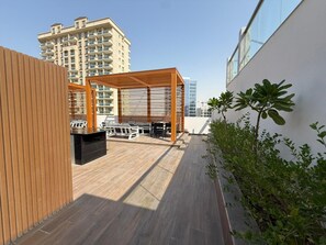 Une terrasse sur le toit, agrémentée d’une pergola en bois, de sièges d’extérieur et offrant une vue sur les immeubles de grande hauteur.