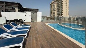A rooftop pool area with lounge chairs and a swimming pool. - Bright and Modern One Bedroom Apartment (Arjan-Dubailand)