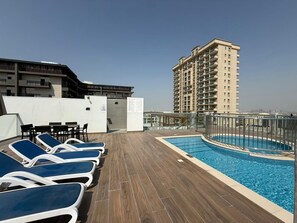 Un espace piscine aménagé sur le toit, avec des chaises longues et une piscine.