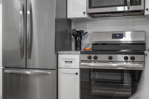 A modern kitchen with stainless steel appliances including a refrigerator, microwave, oven, and stovetop. - Welcome to Vol Haven – Your Home on Rocky Top! (Knoxville)