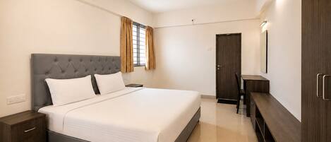 A bedroom with a bed, nightstand, desk, wardrobe, and a ceiling fan.