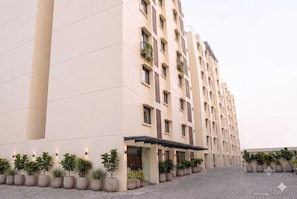 A multi-story hotel with a modern design, featuring a series of balconies and a covered entrance area. - Deluxe Hotel Urban Oasis (Pune)