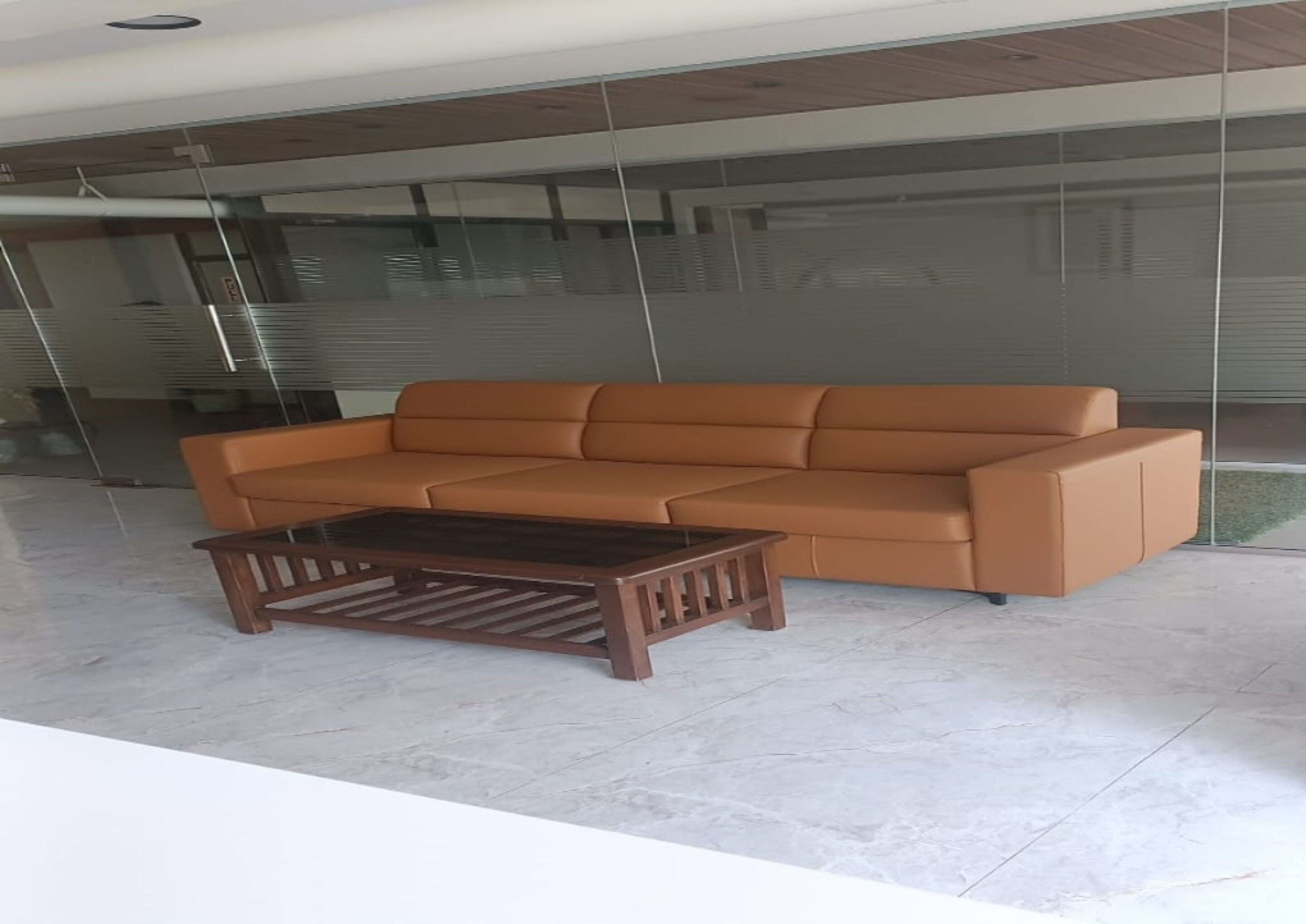 Un interior moderno con un sofá de cuero marrón y una mesa de centro de madera a juego.