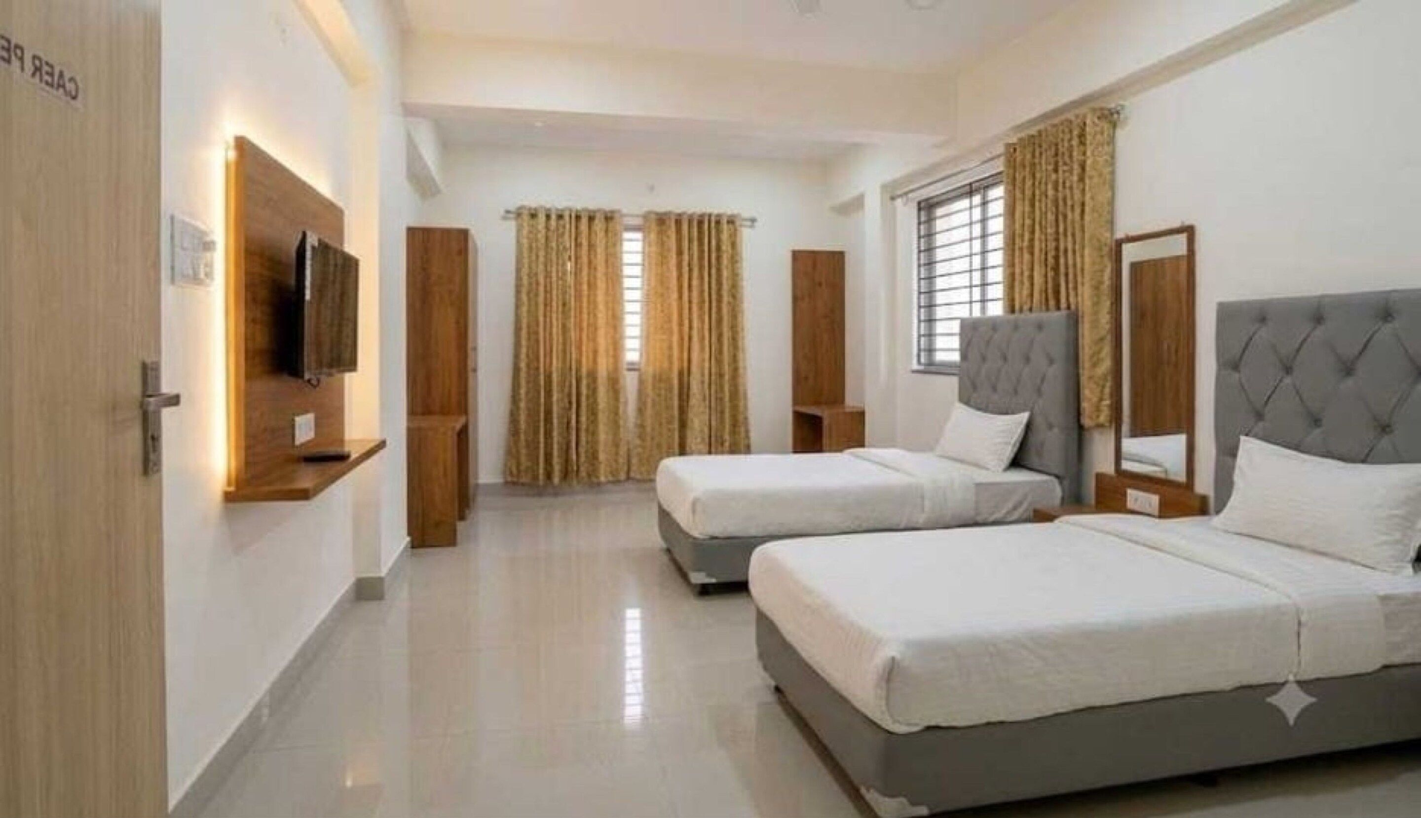 Habitación de hotel con dos camas, televisión y ventana con cortinas.