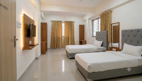 Quarto de hotel com duas camas, televisão e janela com cortinas.