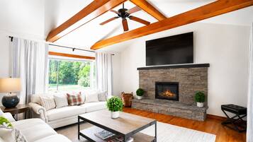 A modern living room with a fireplace, a sofa, a coffee table, and a ceiling fan.