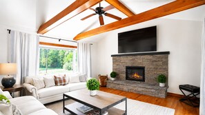 A modern living room with a fireplace, a sofa, a coffee table, and a ceiling fan.