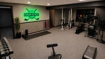 A gym with a neon sign, weight racks, exercise equipment, and a treadmill.