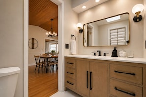 A bathroom with a wooden vanity, a large mirror, and a chandelier.