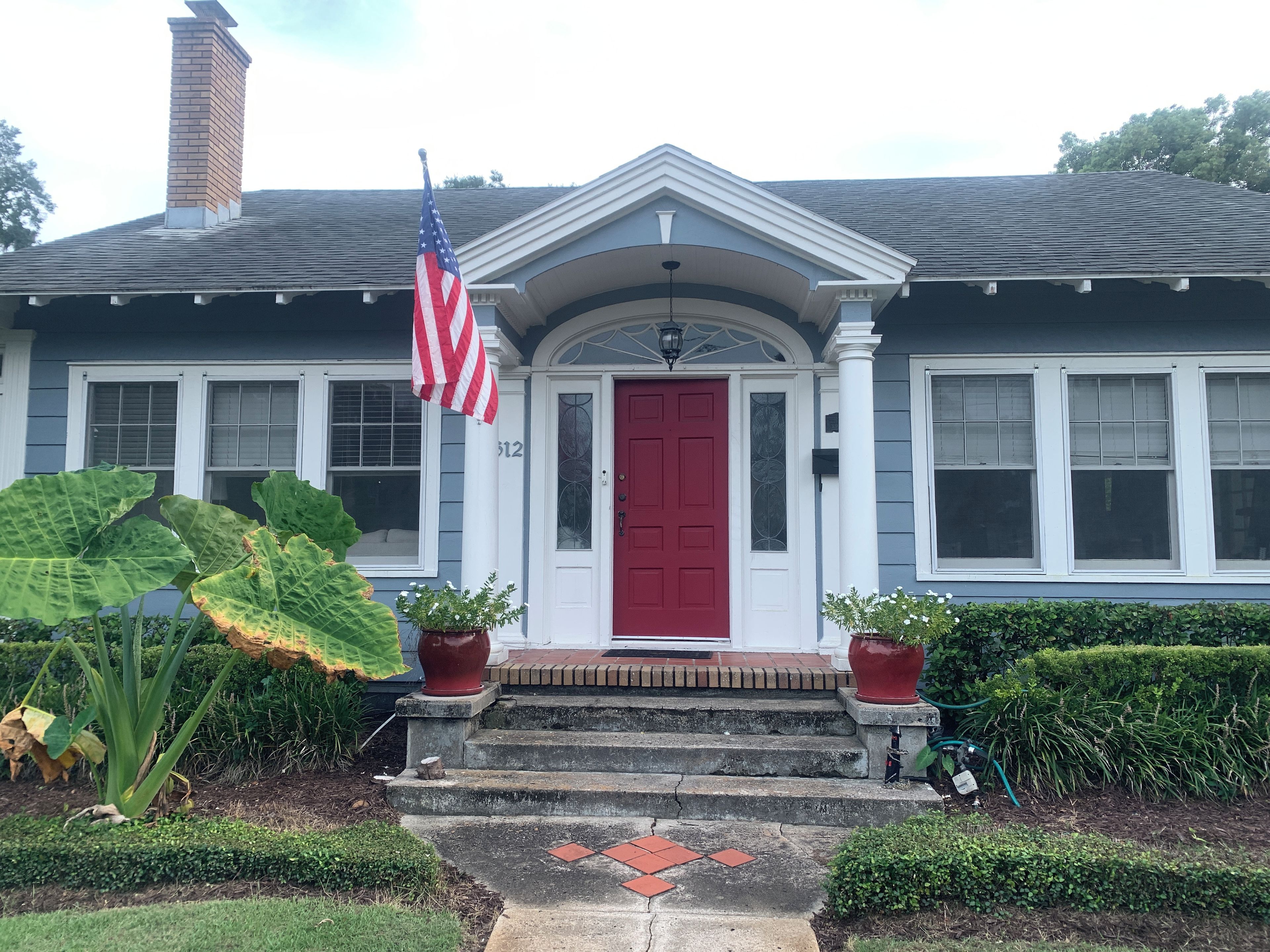 A house with a red door, white columns, and an American flag.