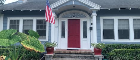 A house with a red door, white columns, and an American flag.