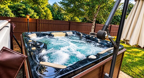Un bain à remous avec jets, entouré d’une terrasse en bois et d’une clôture.
