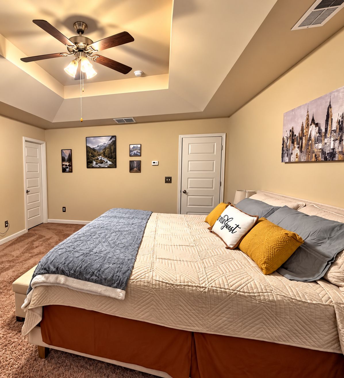 Quarto com uma cama, ventilador de teto, porta e parede com quadros.