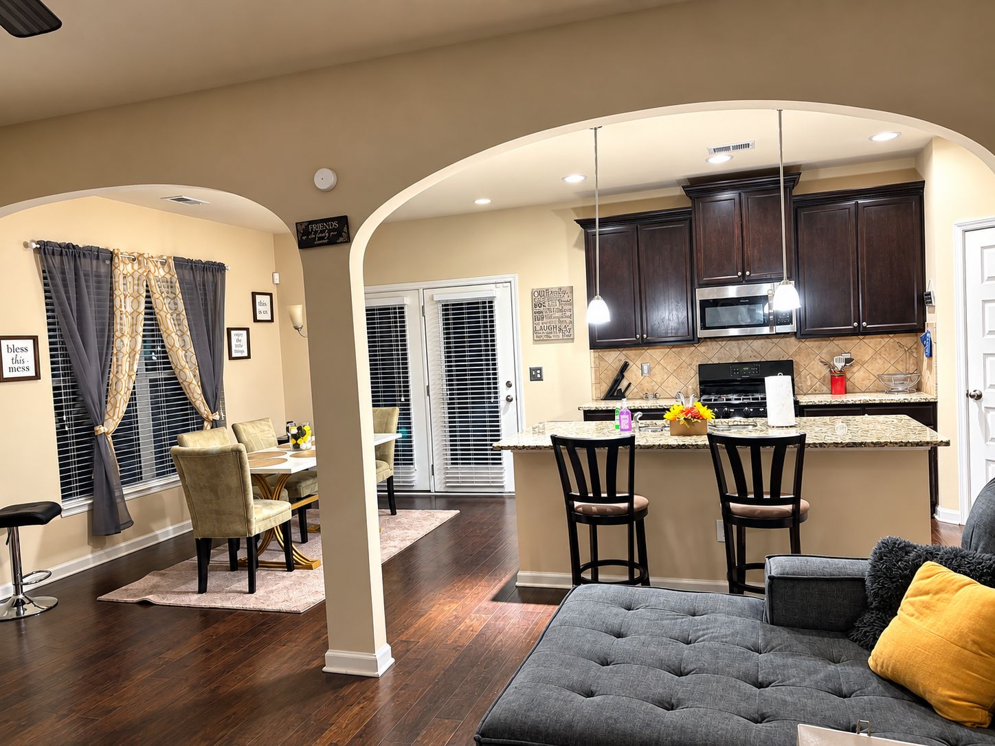 A modern kitchen with dark wood cabinets, a central island, and a dining area with a sofa and chairs.
