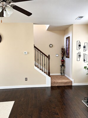 A hallway with a wooden staircase, beige walls, and a ceiling fan. - Spacious 4-bedroom house in fantastic McDonough with Hot Tub (McDonough)