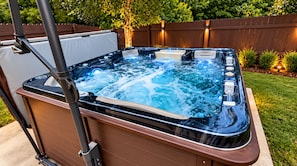 Un jacuzzi con estructura de madera, un panel de control y una terraza de madera alrededor.