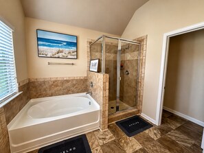 Une salle de bain avec une baignoire, une cabine de douche en verre et un tableau encadré au mur.