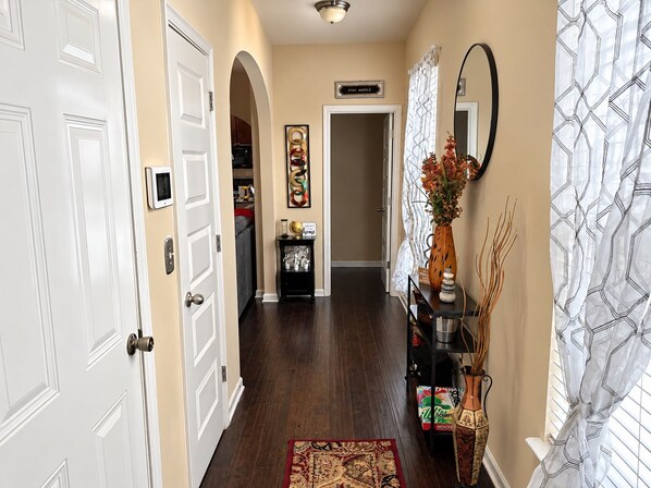 A hallway with a wooden floor, white doors, a black console table with decorative items, and a patterned curtain.