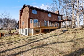 A two-story wooden house with a balcony, situated on a grassy hill. - Big St. Charles Gateway-Deer/Forest View (Saint Charles)