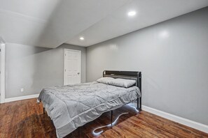 A bedroom with a single bed, a door, and a wooden floor. - Big St. Charles Gateway-Deer/Forest View (Saint Charles)